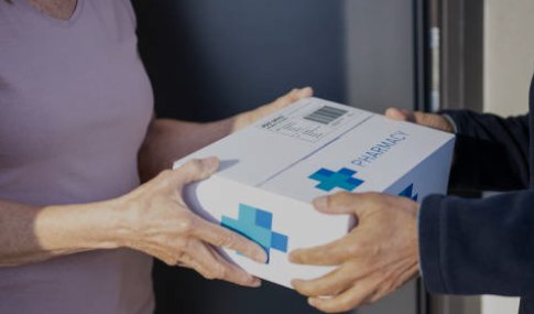 A member receiving a sealed pharmacy delivery at her front door