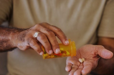 An older man tipping tablets from a prescription bottle into his hand